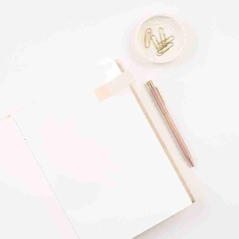 Notepad, pink pen and paperclips