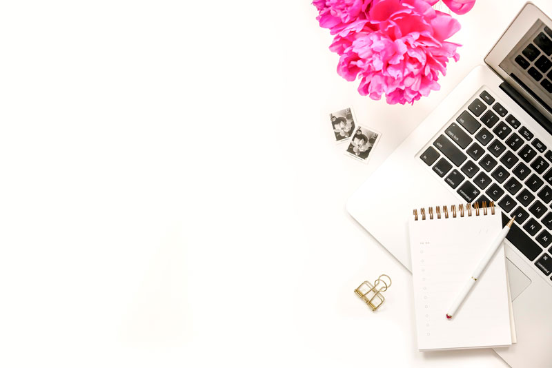 flower on a table with a laptop and notepad